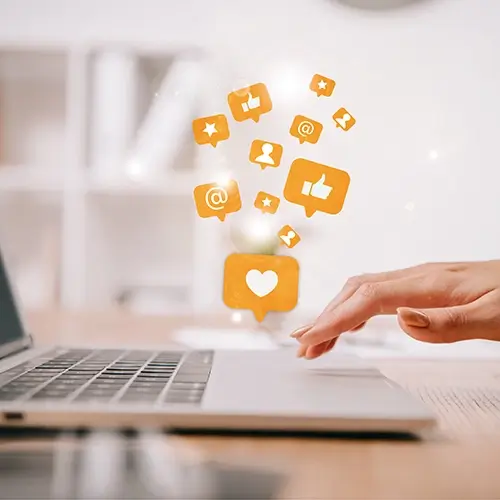 Laptop with orange social media icons floating above the keyboard